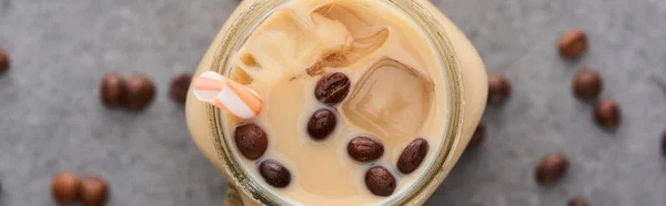 Top view of ice coffee with straw and coffee grains on grey background, panoramic shot — Stock Photo