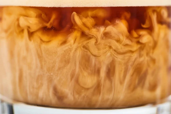 Крупним планом вид на змішування коричневої кави з білим молоком в склі — стокове фото
