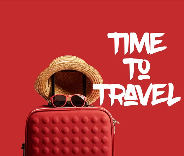 Red colorful travel bag with straw hat and sunglasses isolated on red with time to travel illustration — Stock Photo