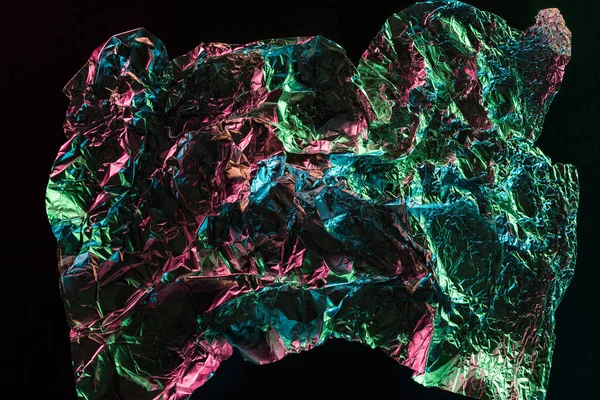 Top view of glossy crumpled foil with colorful lighting reflection in darkness isolated on black — Stock Photo