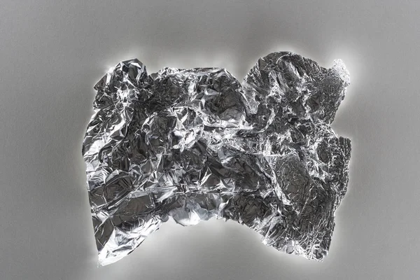 Top view of glossy crumpled silver foil on grey background — Stock Photo