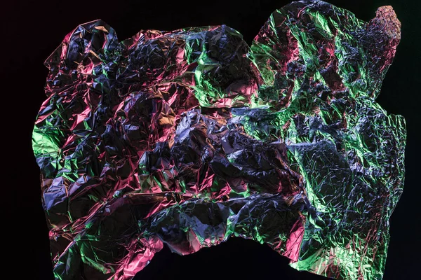 Top view of crumpled foil with colorful reflection in darkness isolated on black — Stock Photo