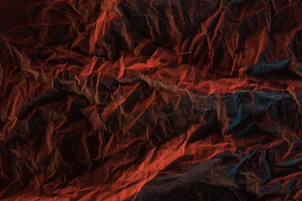 Vista dall'alto di carta accartocciata con illuminazione colorata rossa nel buio — Foto stock