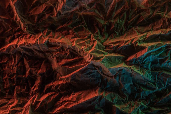 Vue de dessus du papier froissé avec éclairage coloré dans l'obscurité — Photo de stock