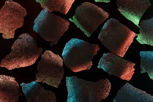 Абстрактный фон из текстурированной рваной серебряной фольги с красочной подсветкой, изолированной на черном — стоковое фото
