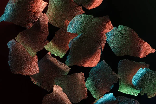 Абстрактний фон шматочків срібної фольги з барвистим освітленням ізольовані на чорному — стокове фото