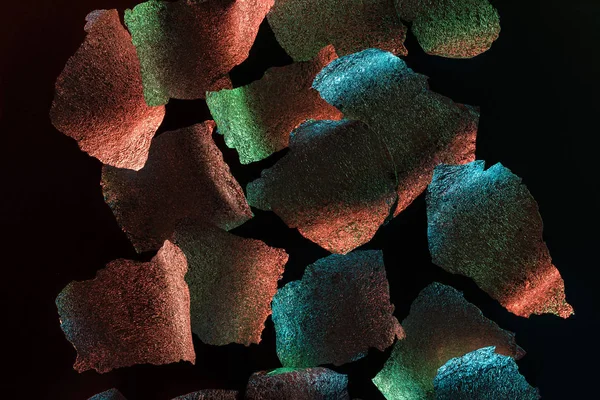 Абстрактний фон шматочків срібної текстури фольги з барвистим освітленням ізольовані на чорному — стокове фото