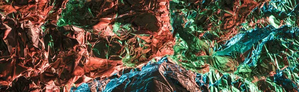 Panoramic shot of glossy crumpled foil with colorful lighting reflection — Stock Photo