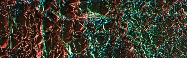 Panoramic shot of glossy crumpled foil with colorful lighting — Stock Photo