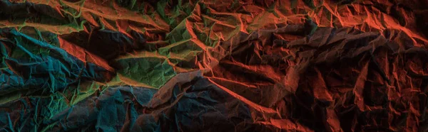 Plan panoramique de papier froissé avec éclairage coloré dans l'obscurité — Photo de stock