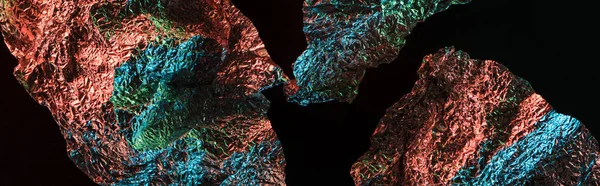 Panoramic shot of ragged textured foil with colorful lighting reflection in darkness isolated on black — Stock Photo