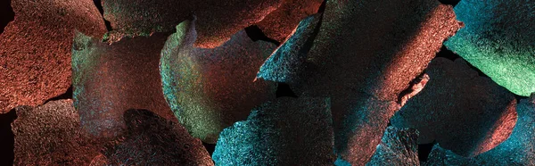 Colpo panoramico di sfondo astratto di foglio ragged con illuminazione colorata isolato su nero — Foto stock