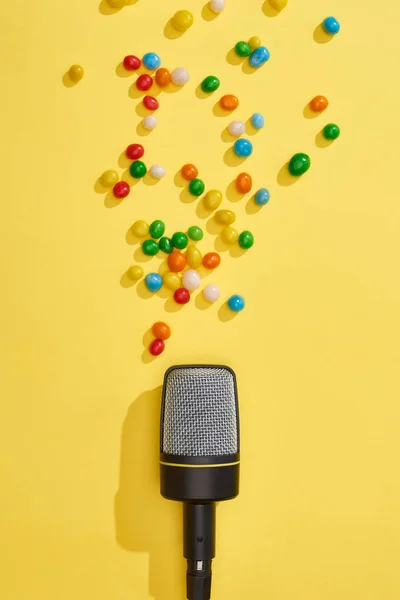 Vista superior del micrófono con caramelos sobre fondo brillante y colorido - foto de stock