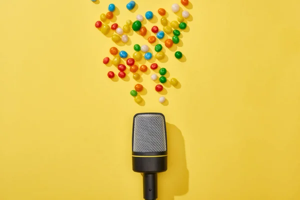 Vista superior de micrófono y caramelos sobre fondo brillante y colorido - foto de stock