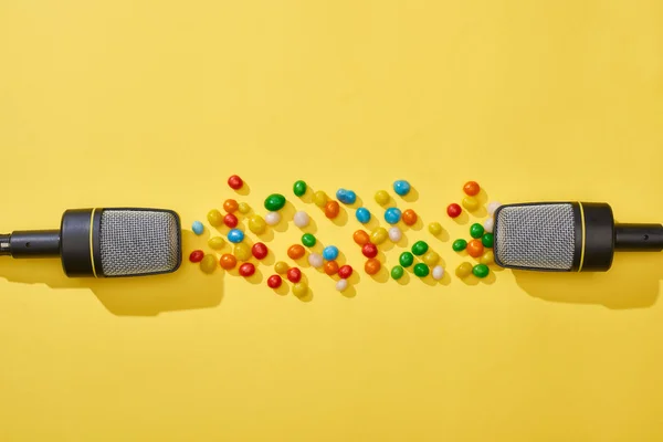 Ansicht von Mikrofonen mit Bonbons auf hellem und buntem Hintergrund — Stockfoto