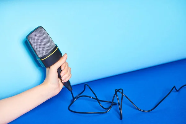 Cropped view of woman holding microphone on turquoise background — Stock Photo