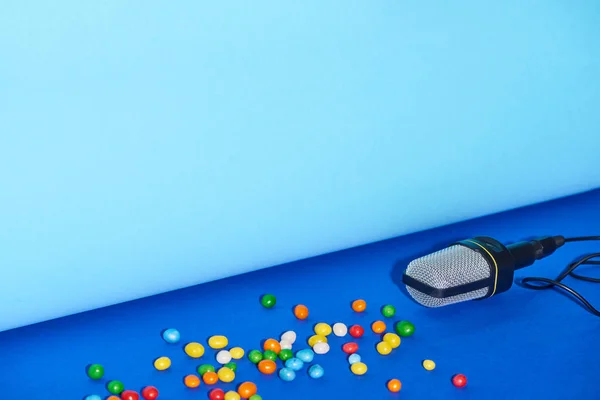 Microfono nero e caramelle su sfondo luminoso e colorato con spazio copia — Foto stock