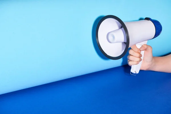 Cropped view of woman holding loudspeaker on turquoise background — Stock Photo