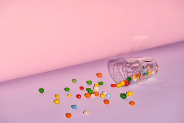 Glas mit süßen Bonbons auf hellem und buntem Hintergrund — Stockfoto