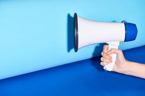 Cropped view of woman holding loudspeaker on turquoise background — Stock Photo