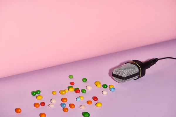 Micrófono negro con caramelos sobre fondo brillante y colorido con espacio de copia - foto de stock