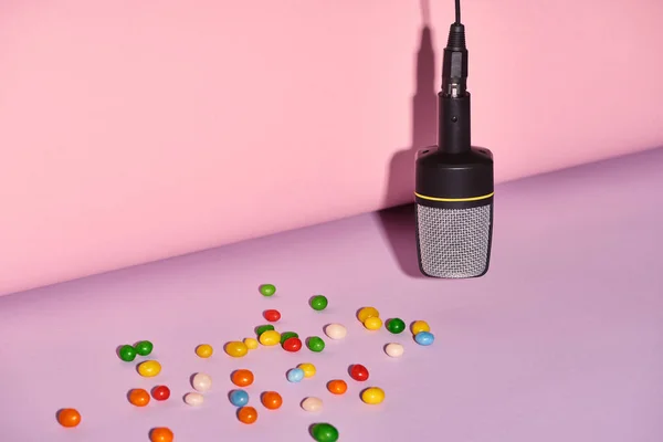 Microphone noir avec bonbons sur fond lumineux et coloré avec espace de copie — Photo de stock