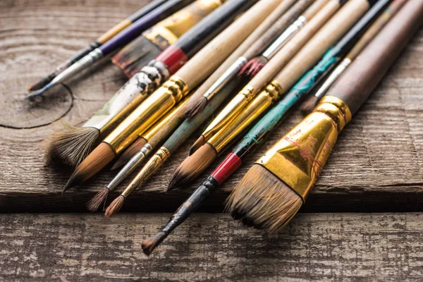 Close up view of old paintbrushes on wooden brown surface — Stock Photo