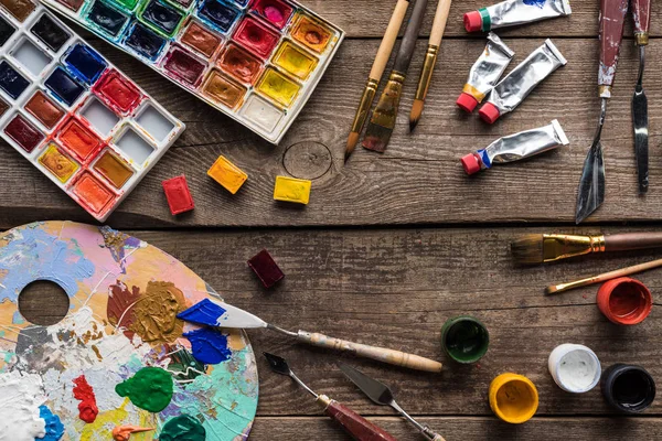 Top view of colorful paints and drawing tools on wooden surface with copy space — Stock Photo