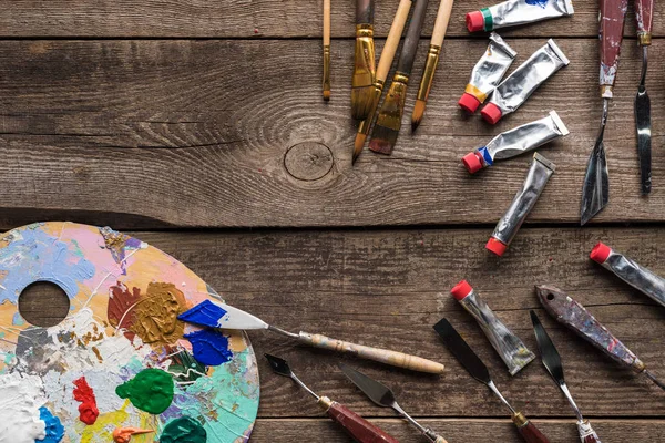 Vista superior da paleta colorida com tintas e ferramentas de desenho na superfície de madeira com espaço de cópia — Fotografia de Stock