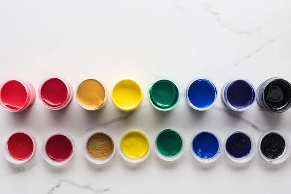 Flat lay with multicolored gouache paints on marble white surface — Stock Photo