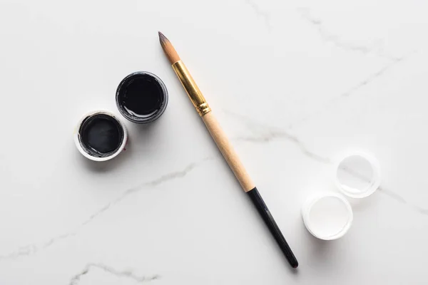 Top view of paints and paintbrush on marble white surface arranged in percent sign — Stock Photo