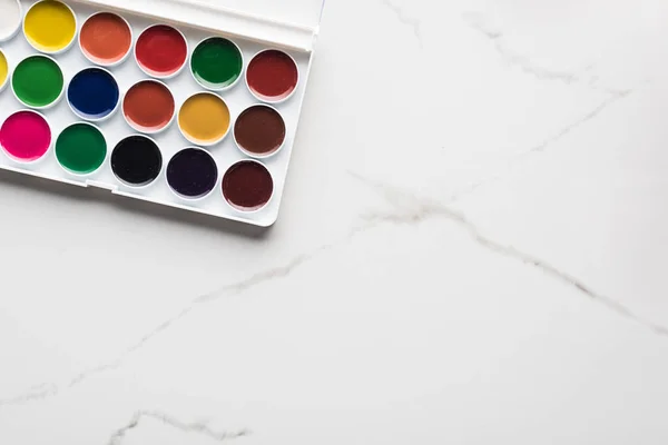 Vista dall'alto della tavolozza di colori ad acquerello su marmo superficie bianca con spazio copia — Foto stock