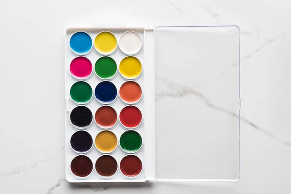 Vista superior da paleta de tinta aquarela aberta na superfície branca de mármore — Fotografia de Stock