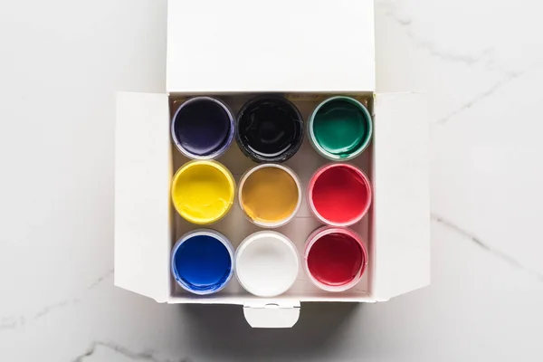Vista dall'alto di colorate vernici guazzo in scatola sulla superficie di marmo — Foto stock