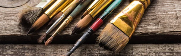 Close up view of old paintbrushes on wooden brown surface, panoramic shot — Stock Photo
