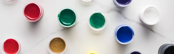 Top view of multicolored bright gouache paints on marble white surface, panoramic shot — Stock Photo