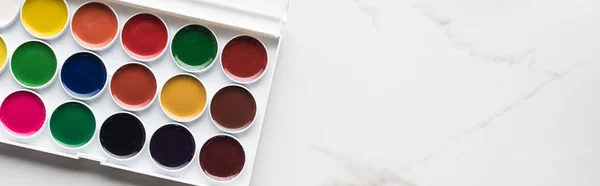 Top view of watercolor paint palette on marble white surface with copy space, panoramic shot — Stock Photo