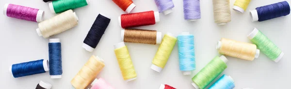 Panoramic shot of bright and colorful threads on white background — Stock Photo