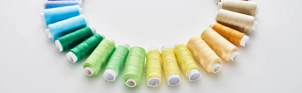 Panoramic shot of bright and colorful threads on white background — Stock Photo