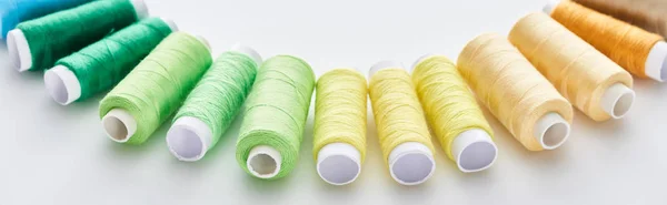 Panoramic shot of bright and colorful threads on white background — Stock Photo