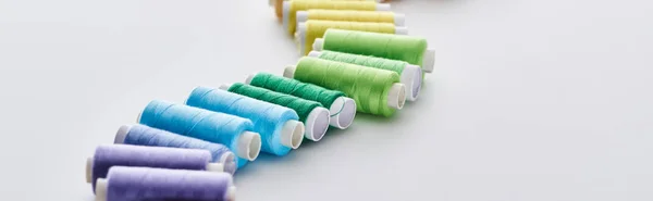 Panoramic shot of bright and colorful threads on white background — Stock Photo