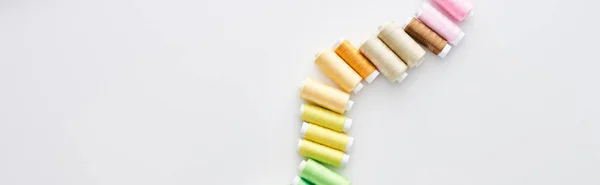 Panoramic shot of bright and colorful threads on white background — Stock Photo