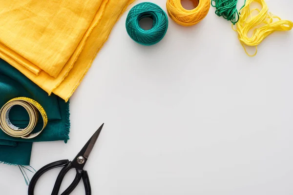 Top view of fabric, knitting yarn balls, measuring tape, scissors and threads on white background — Stock Photo