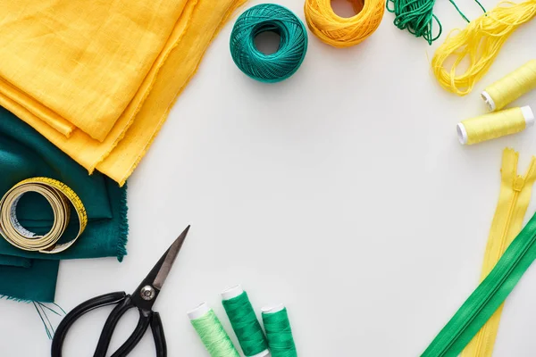 Top view of fabric, knitting yarn balls, measuring tape, scissors and threads on white background — Stock Photo