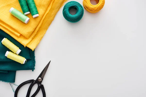 Top view of fabric, knitting yarn balls, scissors and threads on white background — Stock Photo