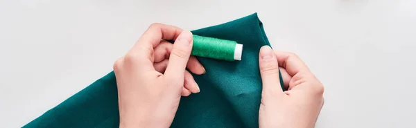 Tiro panorâmico de costureira segurando tecido colorido e linha no fundo branco — Fotografia de Stock