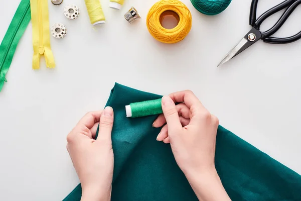 Vue du dessus de couturière tenant tissu coloré et fils sur fond blanc — Photo de stock