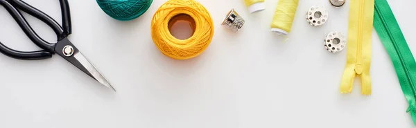 Panoramic shot of scissors, knitting yarn balls, zippers, threads, thimble and bobbins on white background — Stock Photo