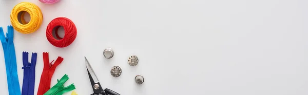 Panoramic shot of zippers, scissors, thimbles, knitting yarn balls, bobbins on white background — Stock Photo