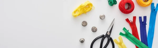 Panoramic shot of zippers, scissors, thimbles, threads, knitting yarn balls, bobbins on white background — Stock Photo